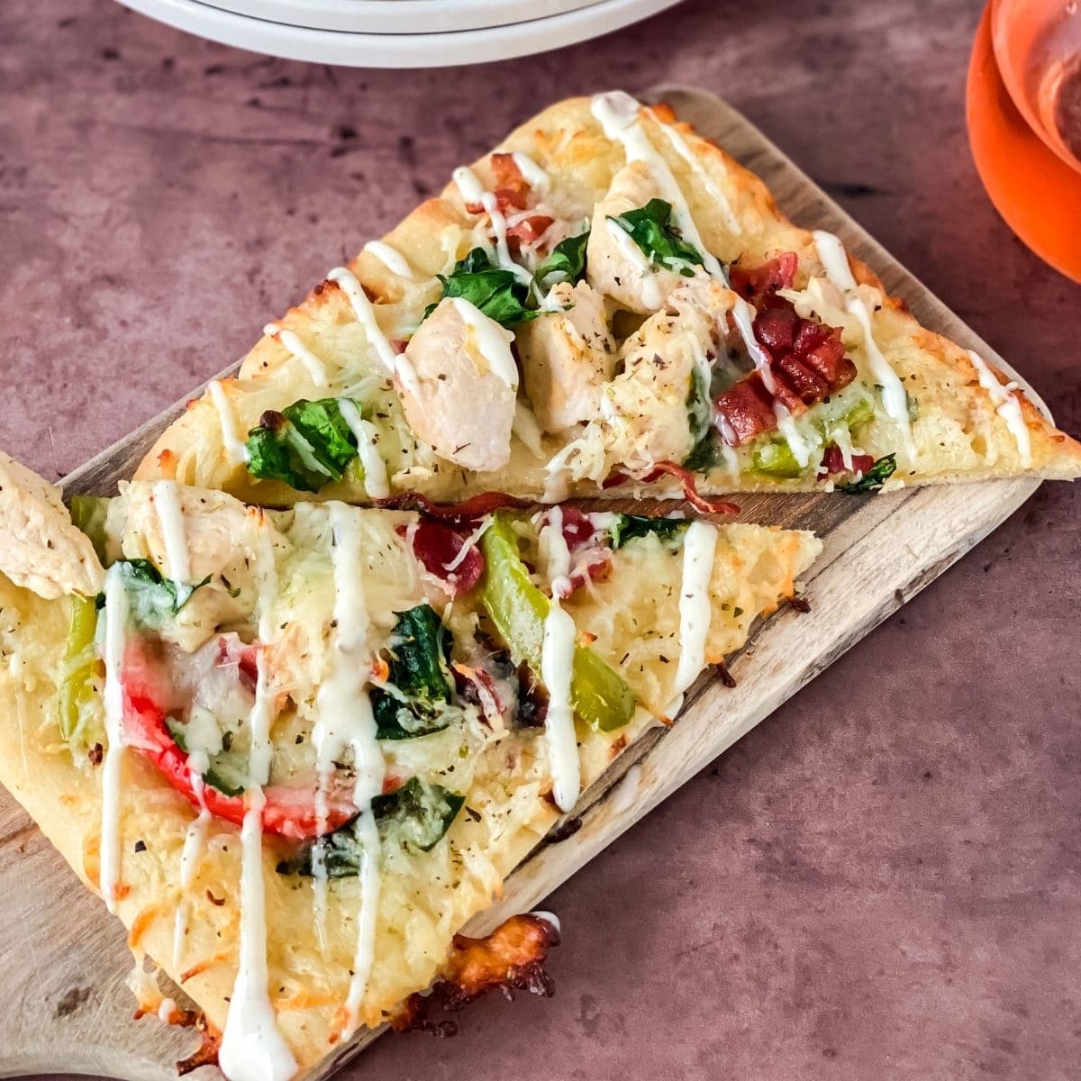 flatbread pizza on pink table with white plate in background