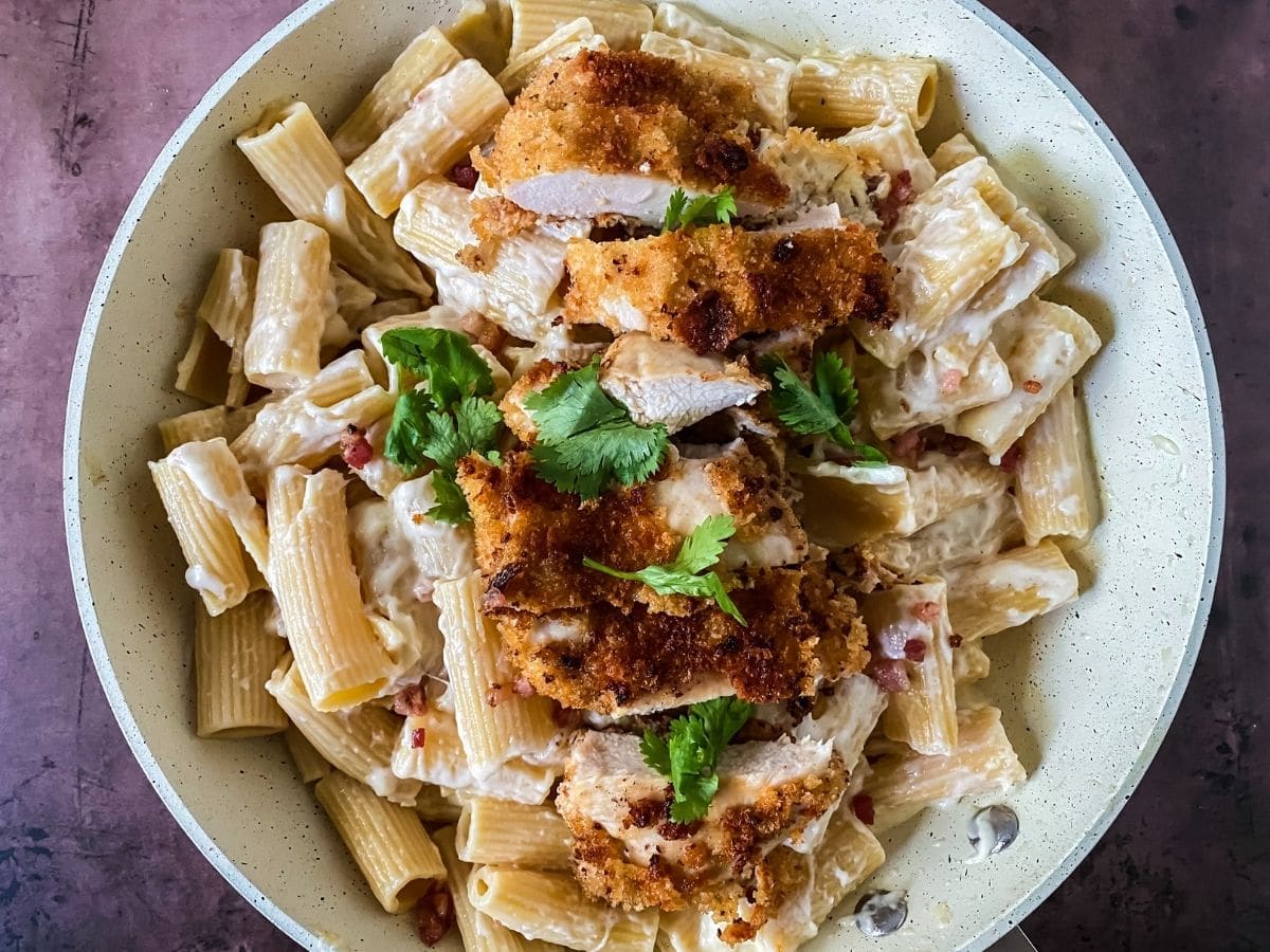 round white bowl of pasta with chicken and parsley on top