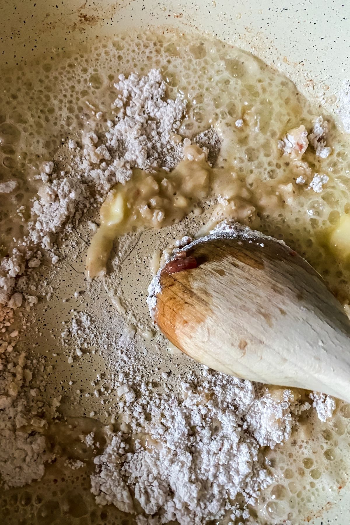 wooden spoon stirring flour into butter in skillet
