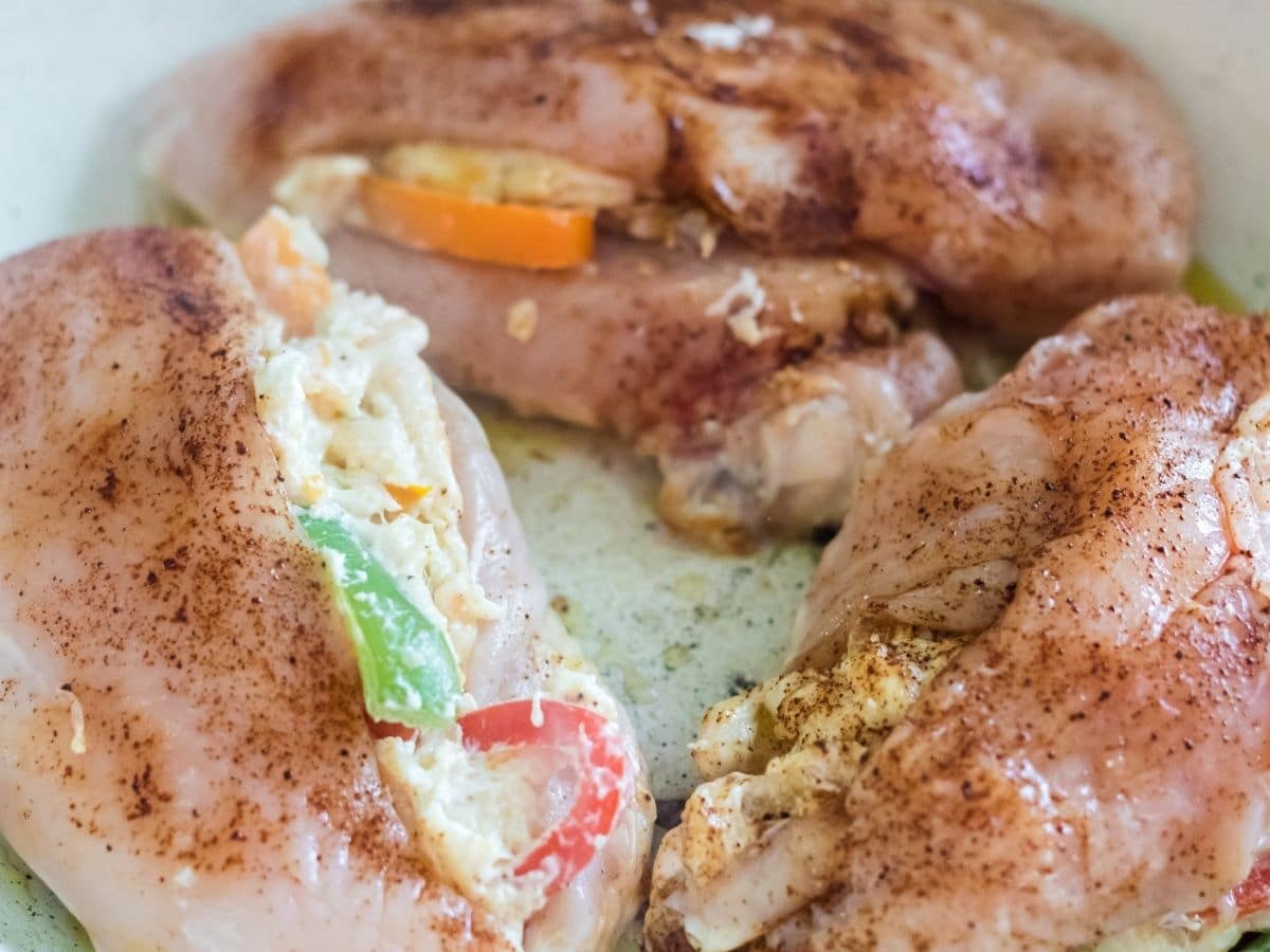 raw chicken breasts in white skillet being cooked