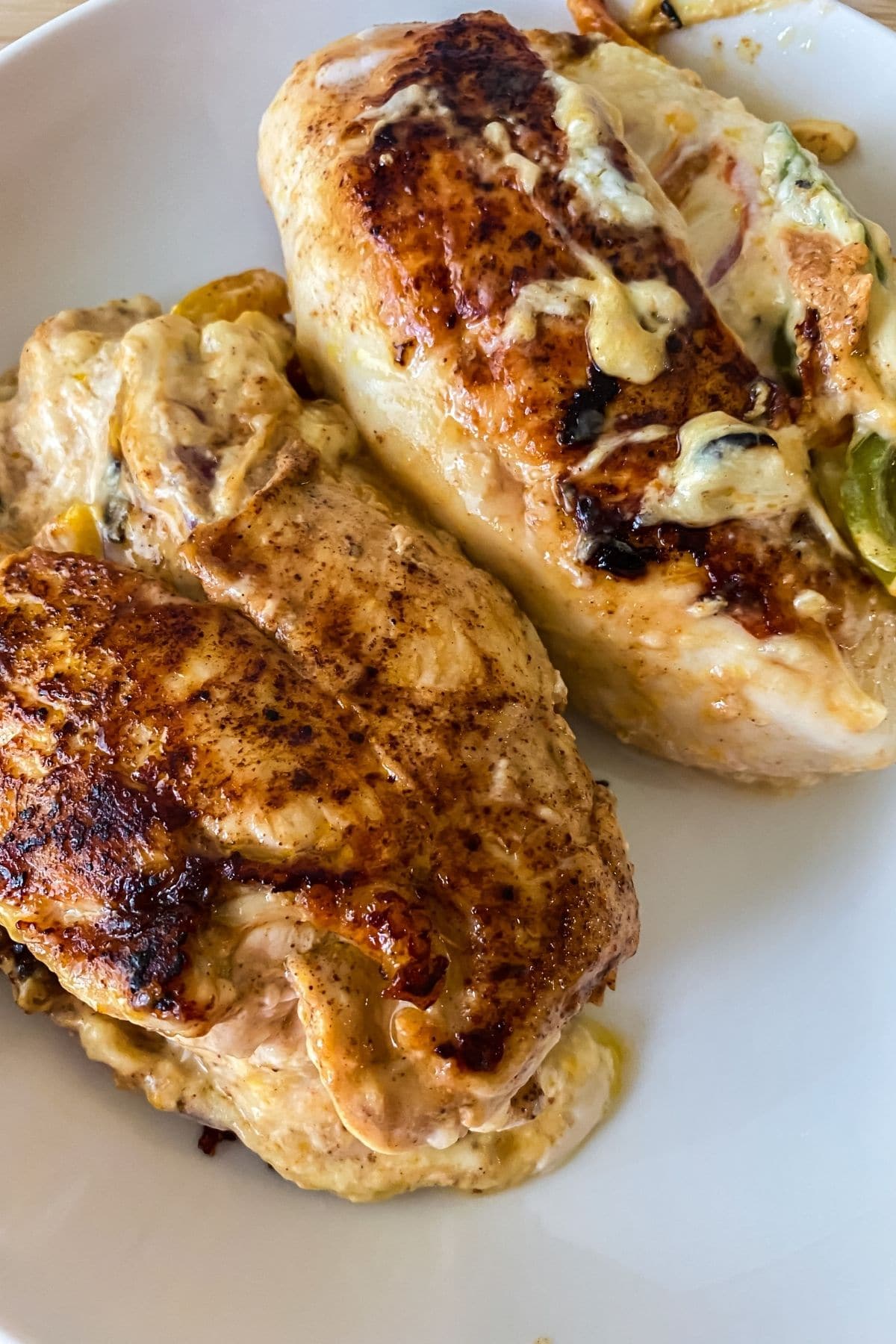 two chicken breasts on plate with cheese stuffing