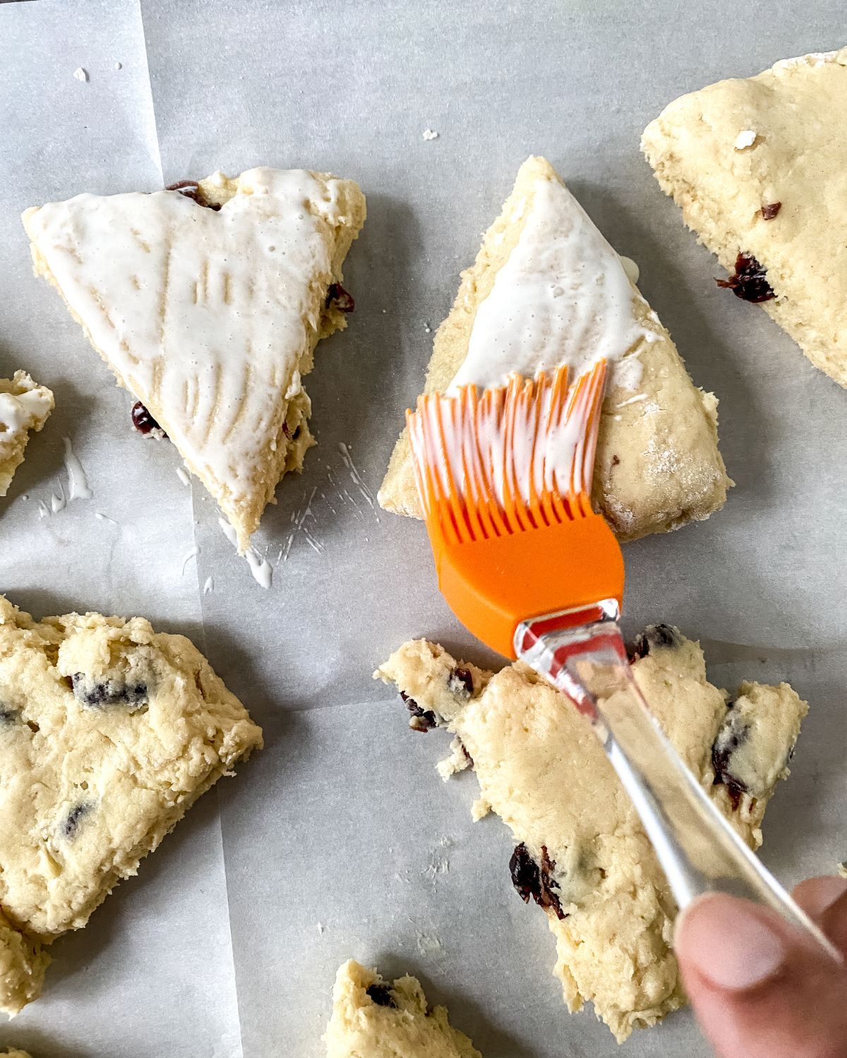 orange pastry brush brushing cream over top of scones