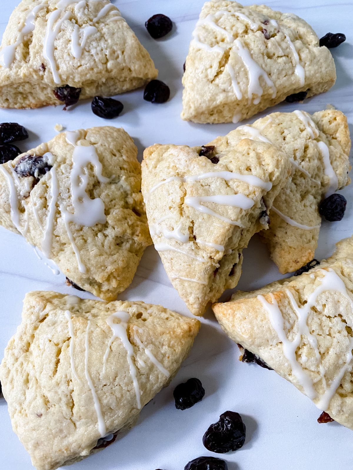 stacks of scones on white table with dried cherries beside them