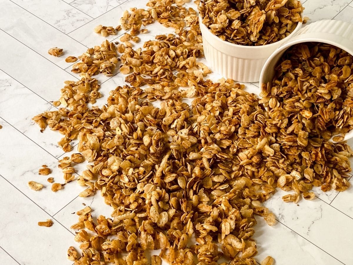 two round white ramekins of granola with more granola on table