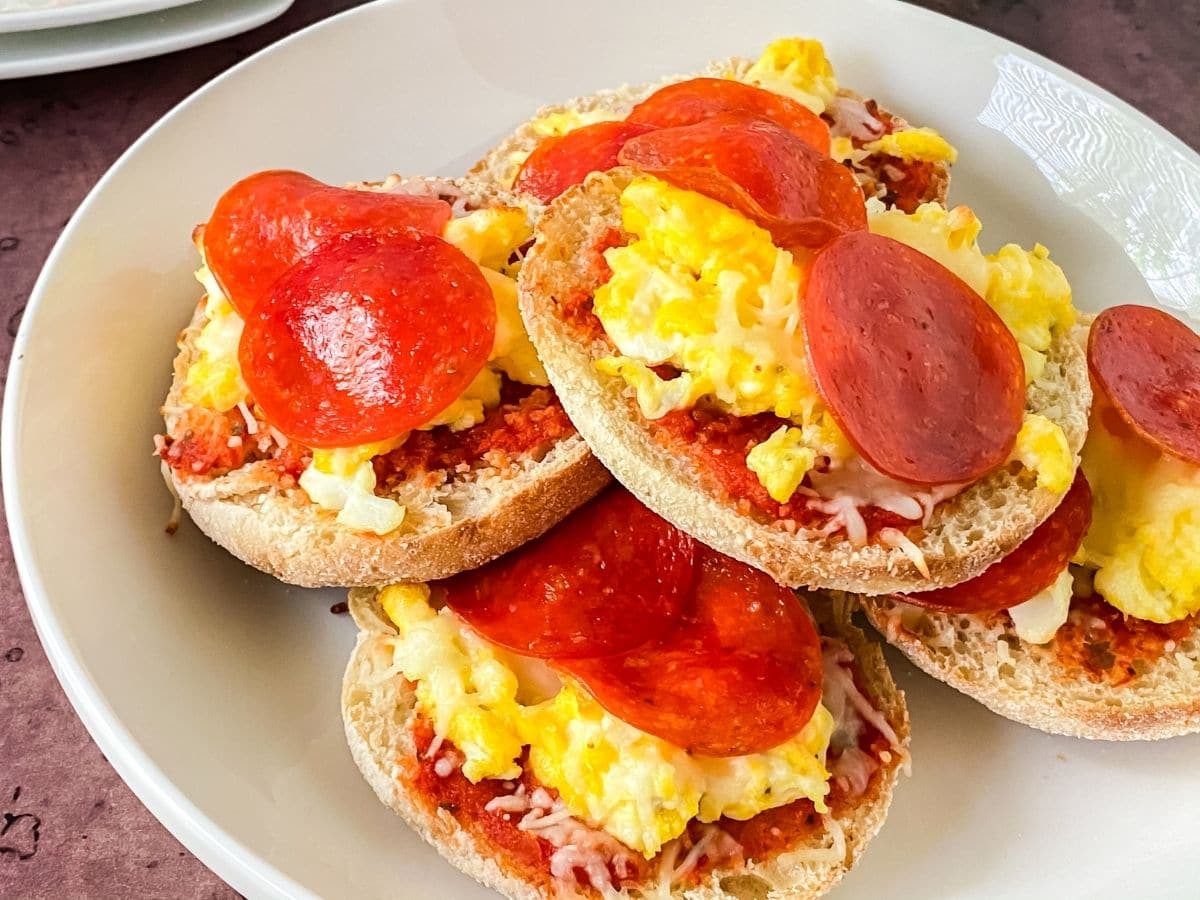 english muffins topped with eggs and pepperoni on white plate