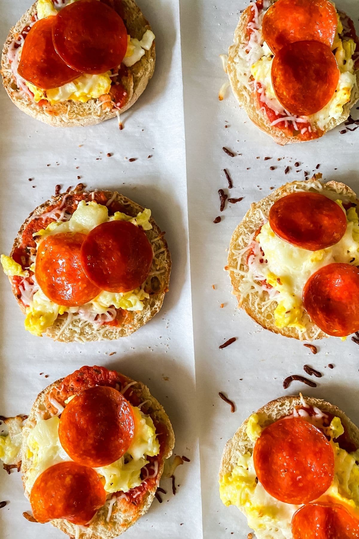 baked english muffin pizzas on parchment paper