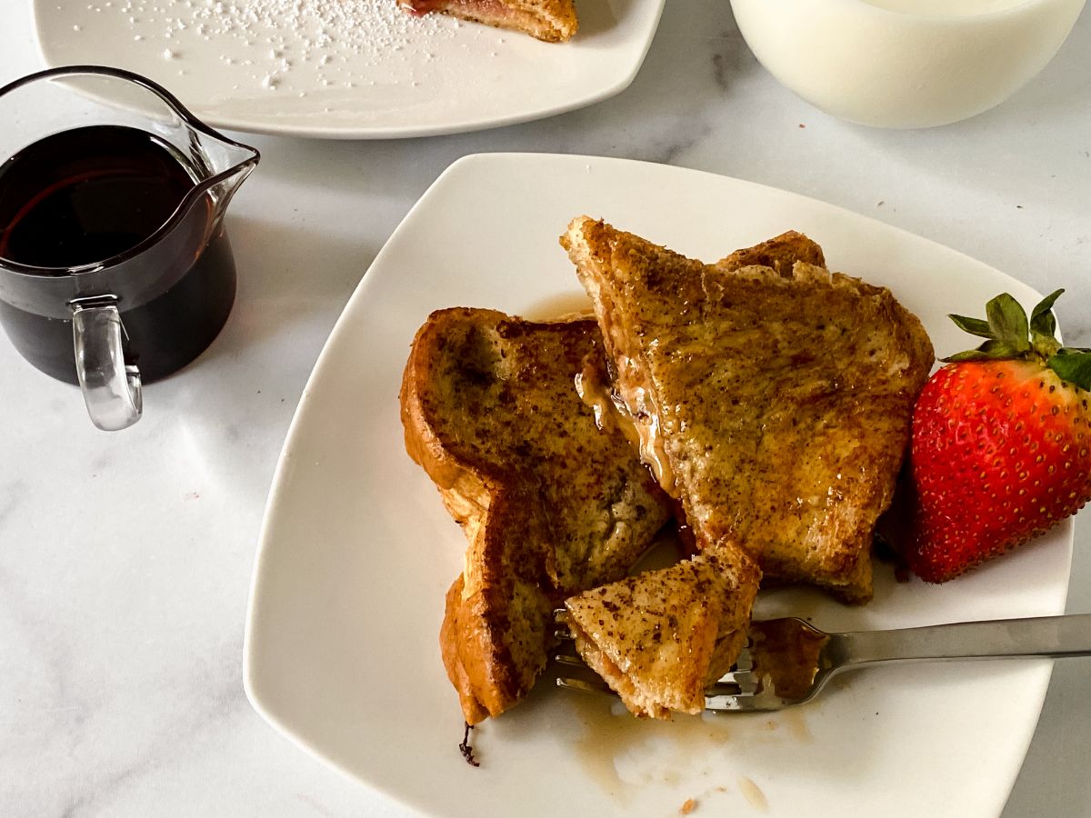 two slices french toast on white plate on marble table
