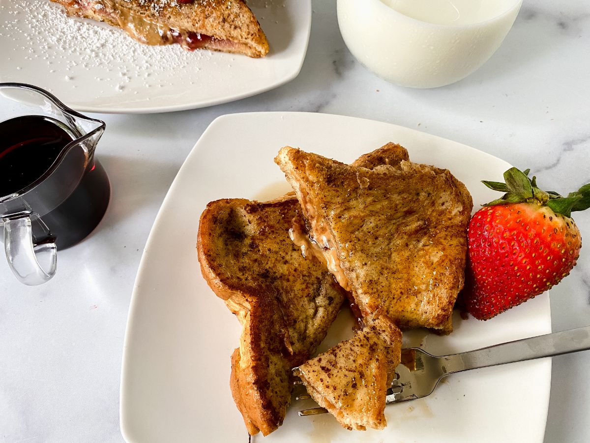 sliced french toast on square white plate with berry on plate