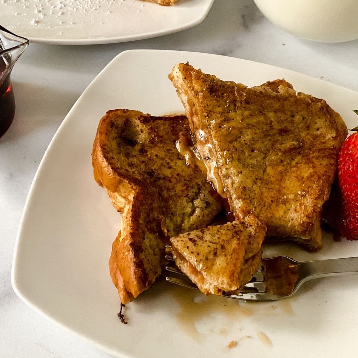 two slices french toast on white plate on marble table