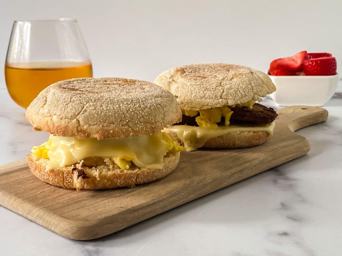 two English muffin sandwiches on cutting board sitting on marble table