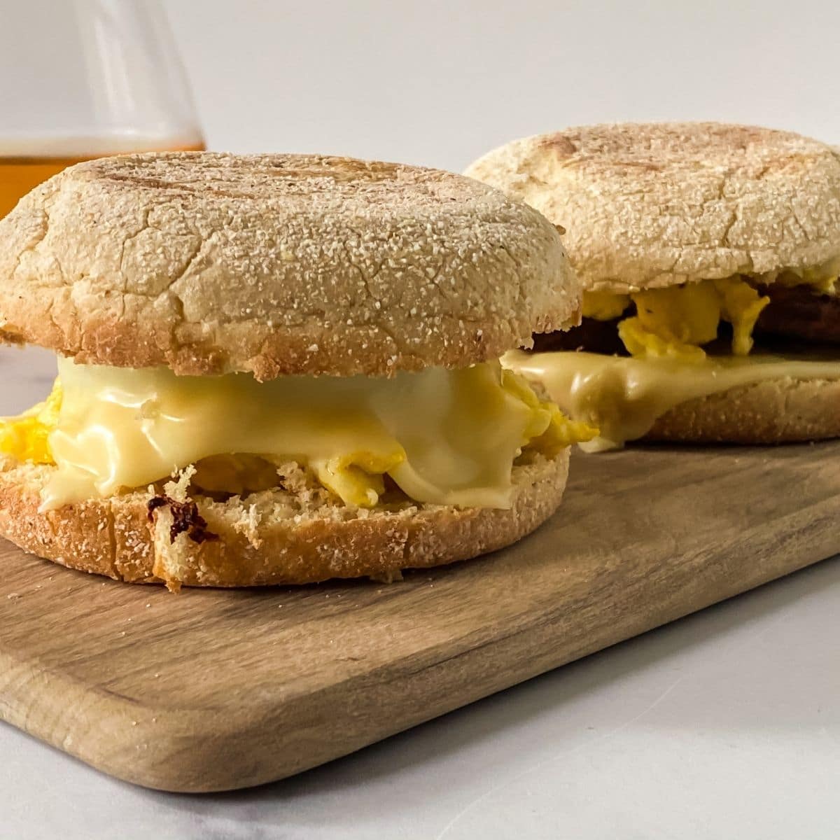 egg and sausage mcmuffin sandwiches on cutting board