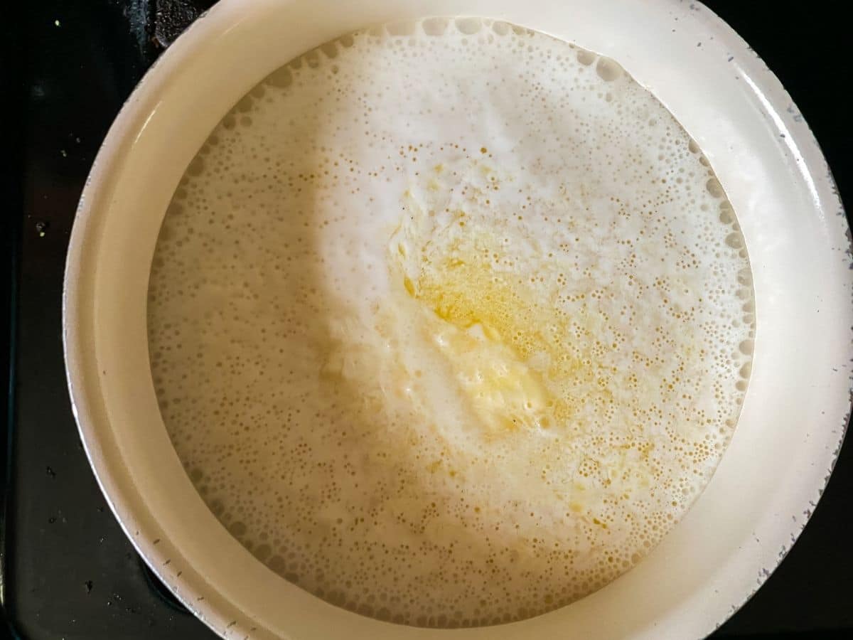 uncooked grits in saucepan with milk and butter