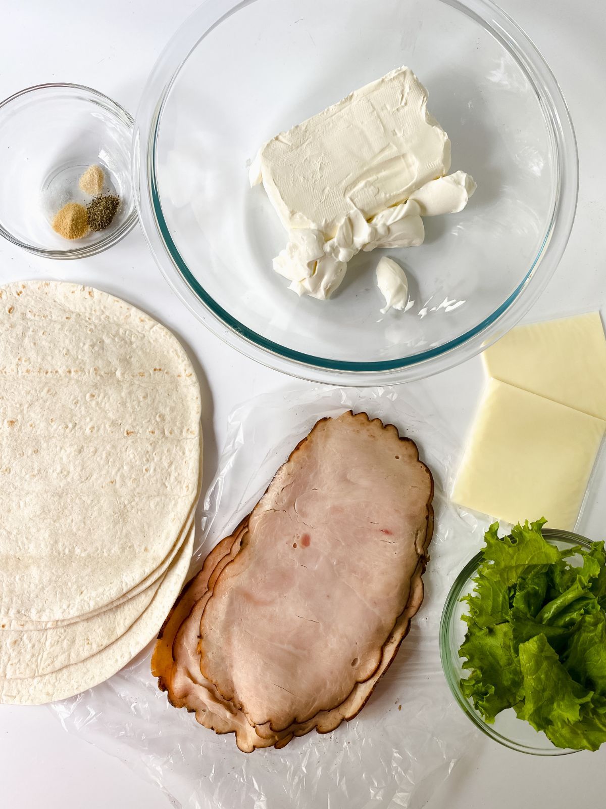 tortilla, turkey, cheese, romain lettuce, and cream cheese on white table