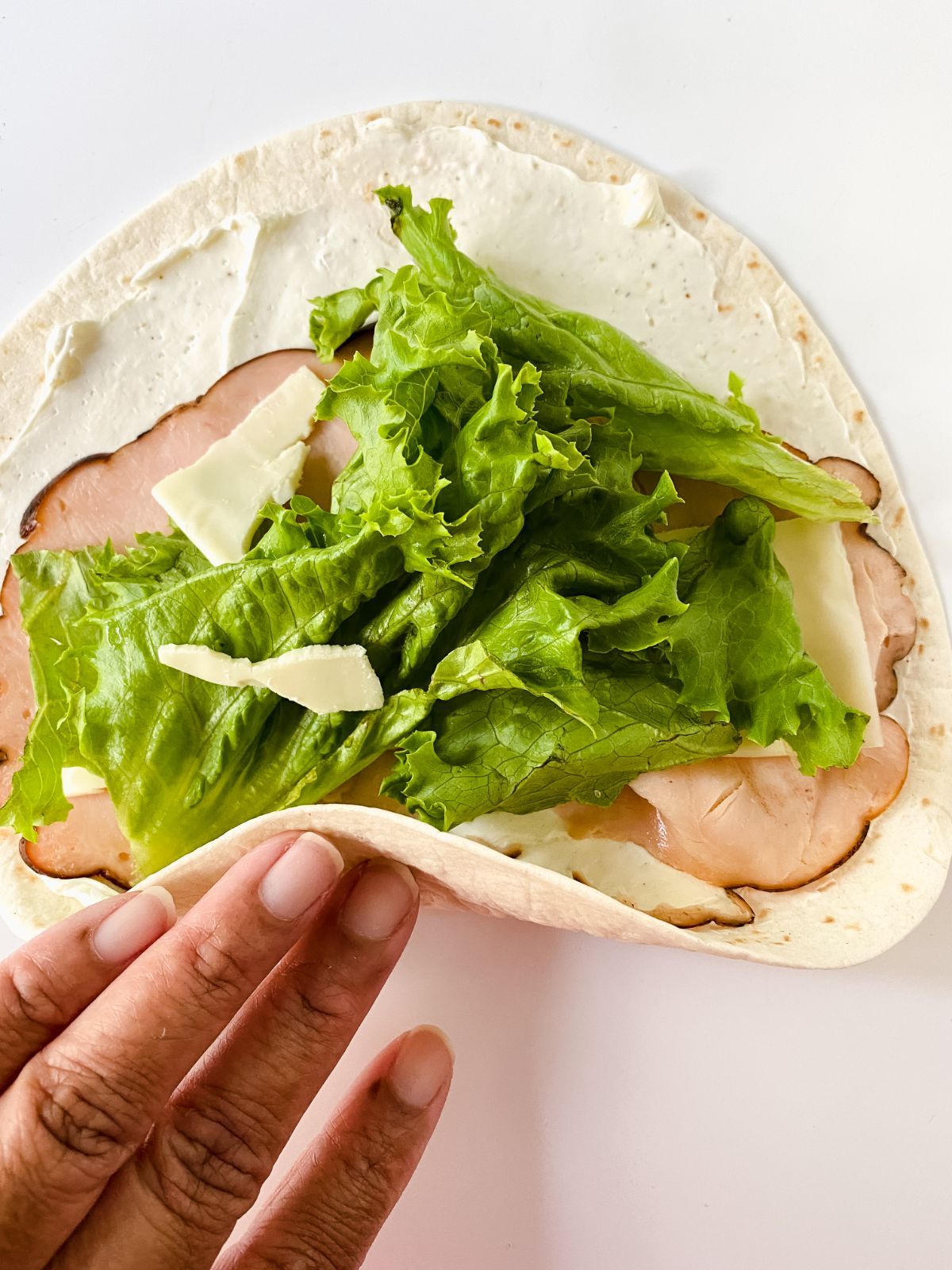 flour tortilla with turkey and lettuce held in hand