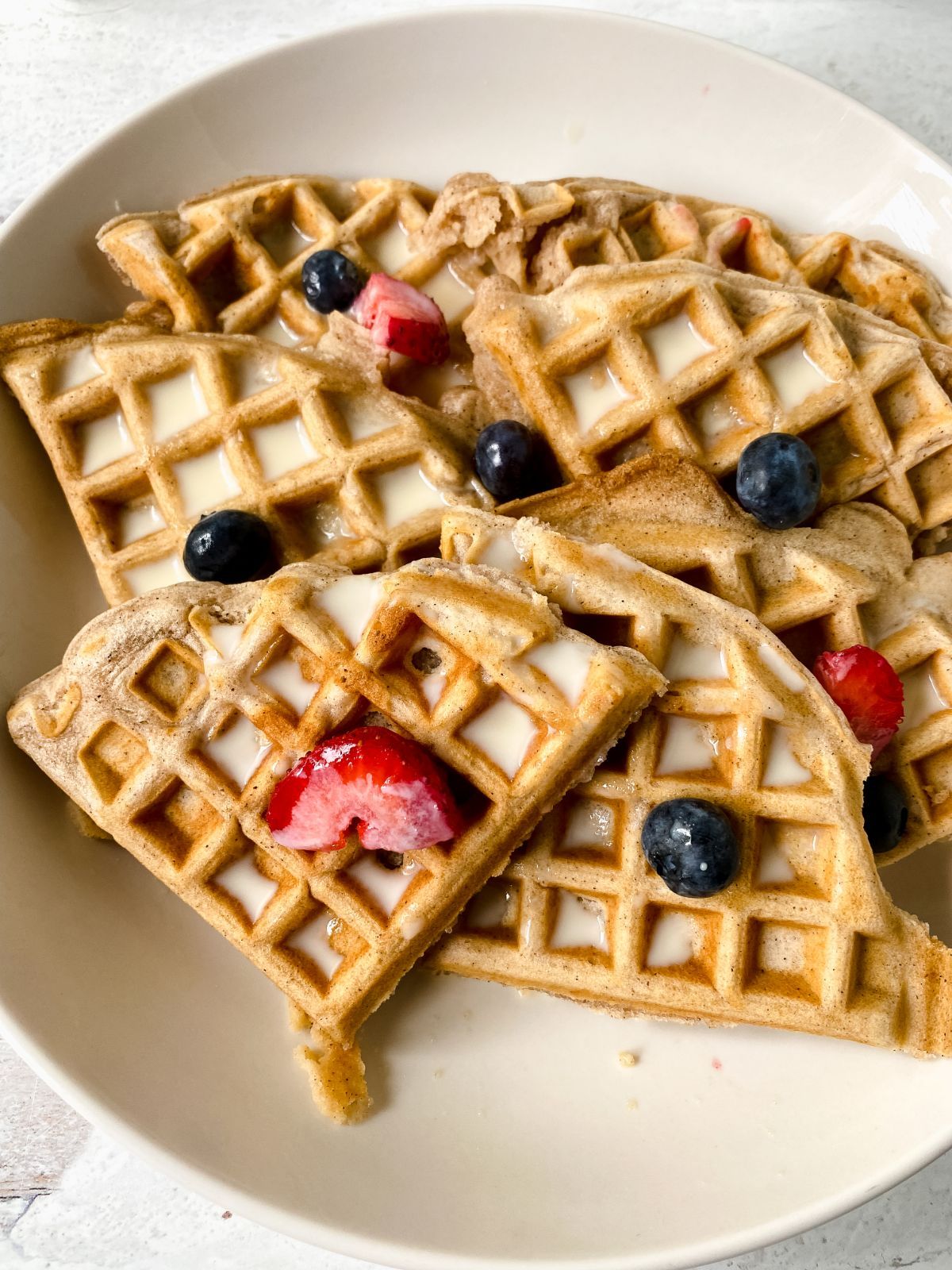 round white plate with triangle waffles topped with berries and syrup