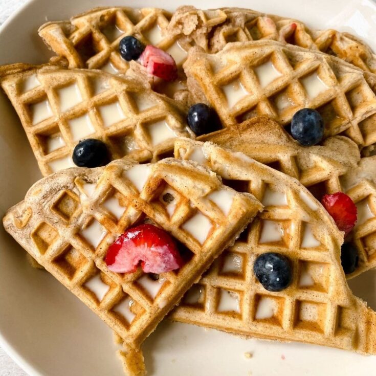 cream plate of waffles with berries on top