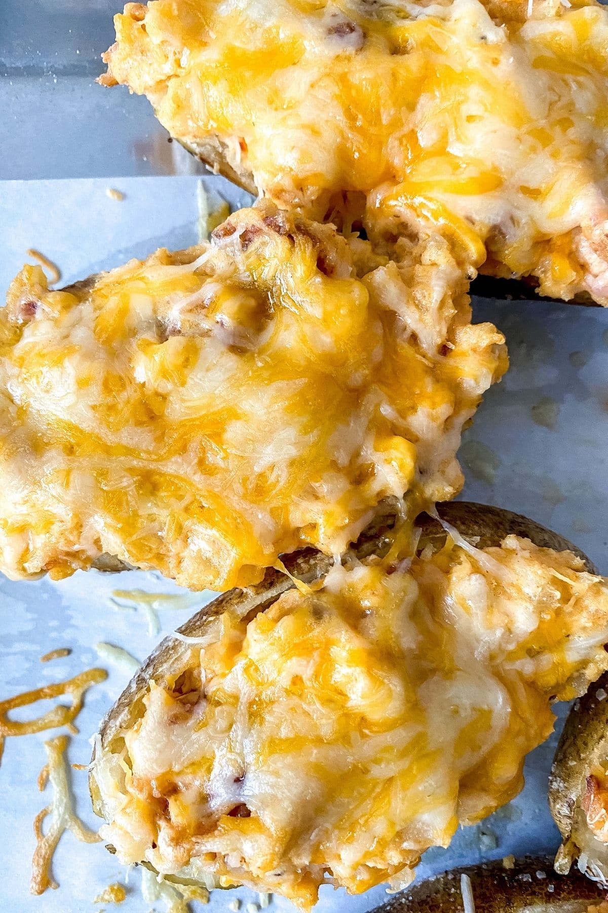 twice baked potatoes topped with cheese on parchment paper