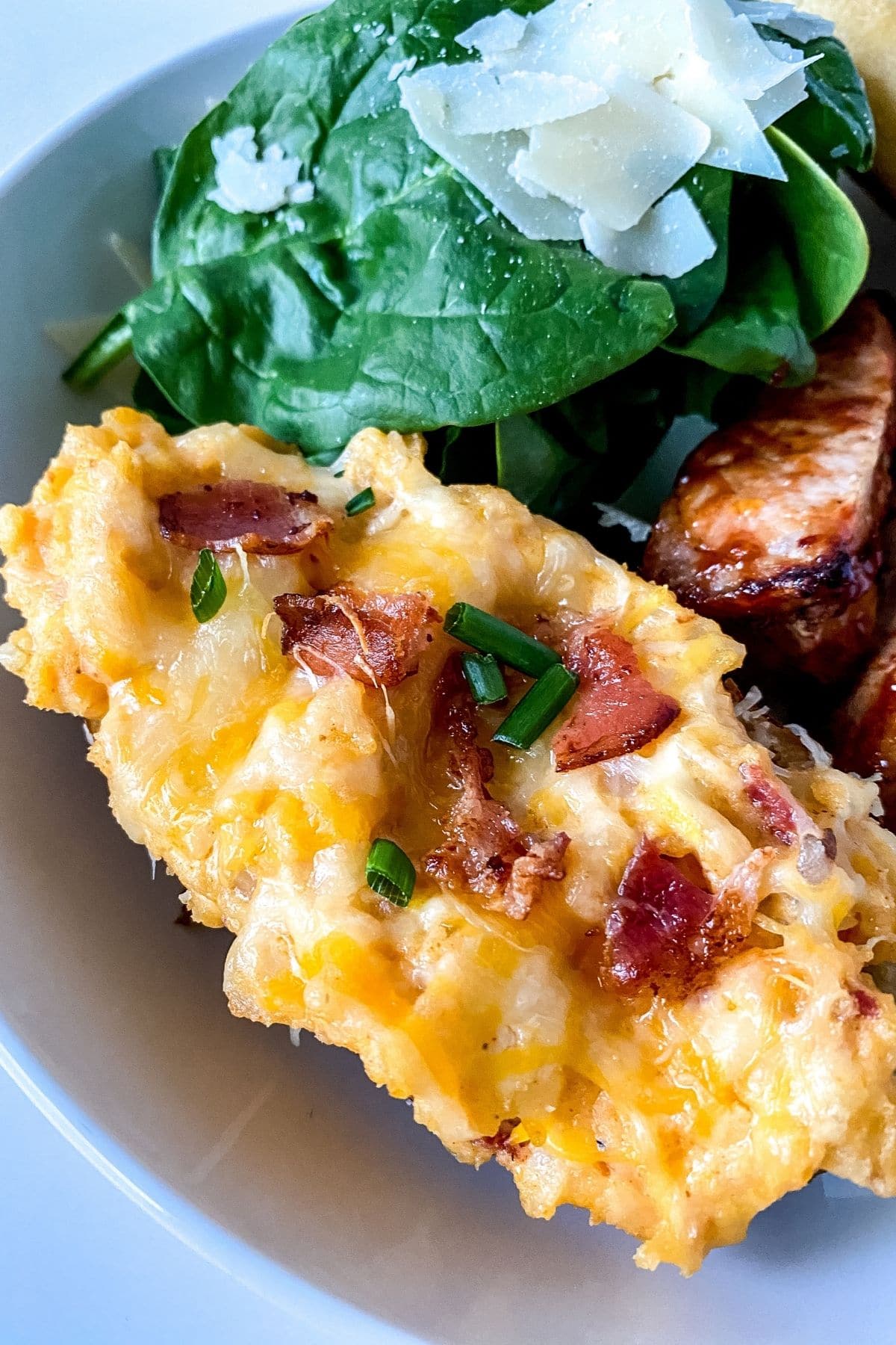 twice baked potato with bacon on top on plate with salad