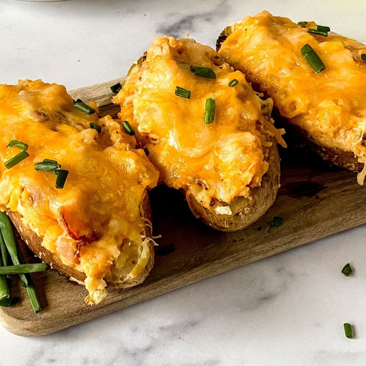 twice baked potatoes on wood cutting board on marble table