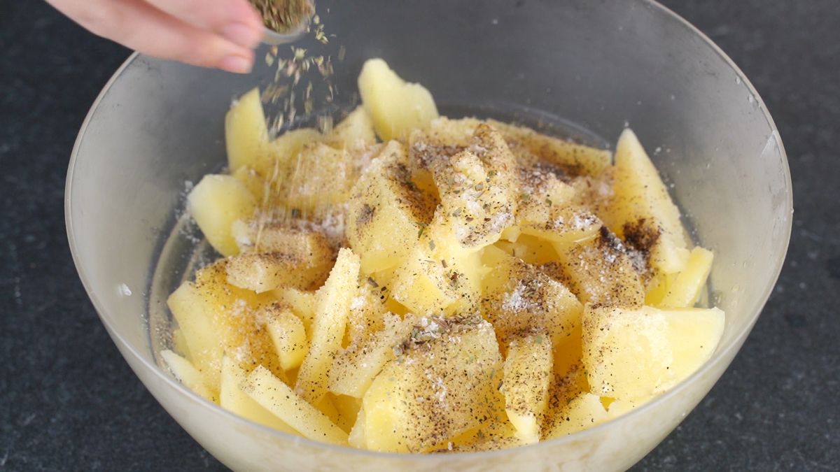 hand sprinkling seasonings on cooked potatoes