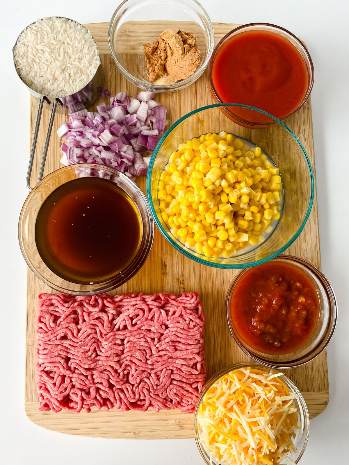cutting board with ground beef on one corner and bowls of salsa corn and broth