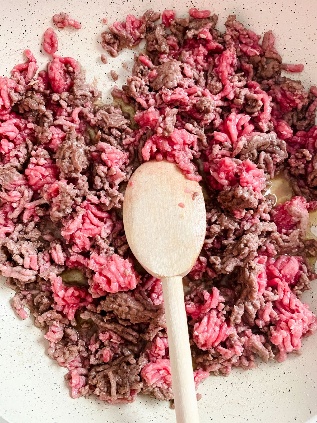 ground beef in skillet with wooden spoon