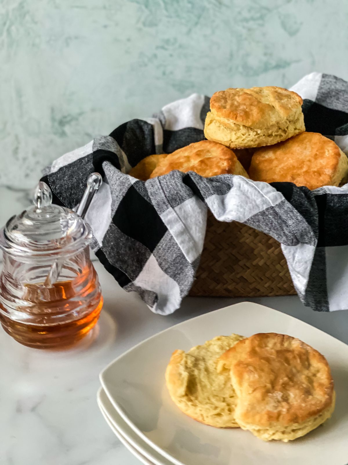 basket of biscuits behind white saucer holding single biscuit