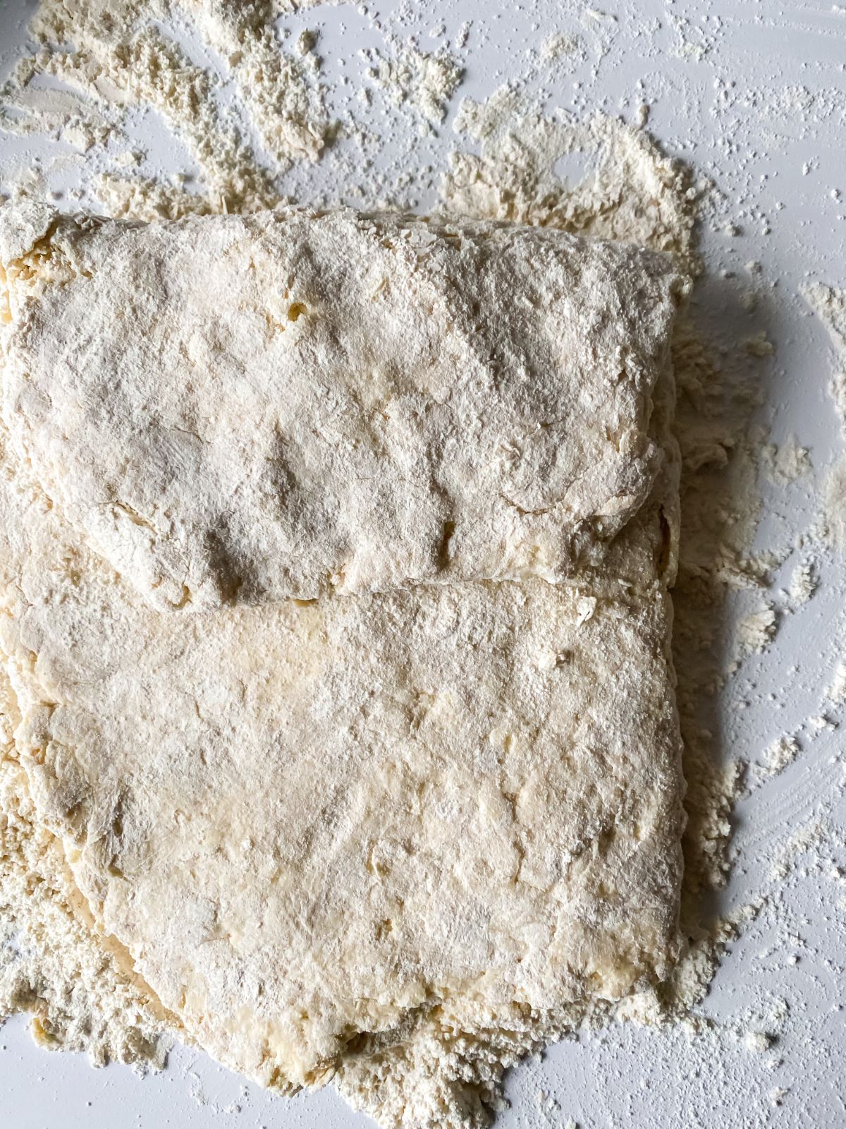 biscuit dough folded over itself on white table