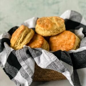 basket with black and white plaid napkin holding biscuits