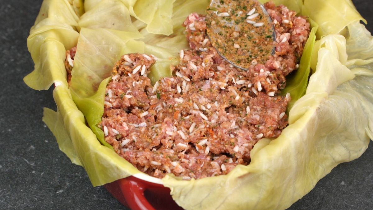 spreading ground meat and rice over cabbage leaves