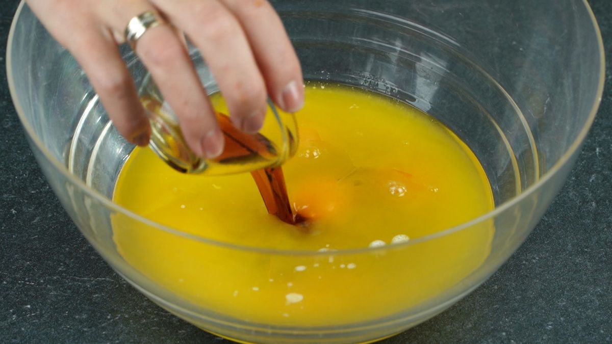 hand pouring vanilla extract into bowl of eggs