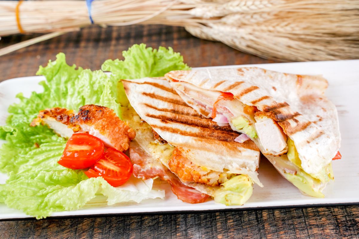 tortilla wrap on white platter with lettuce and tomato
