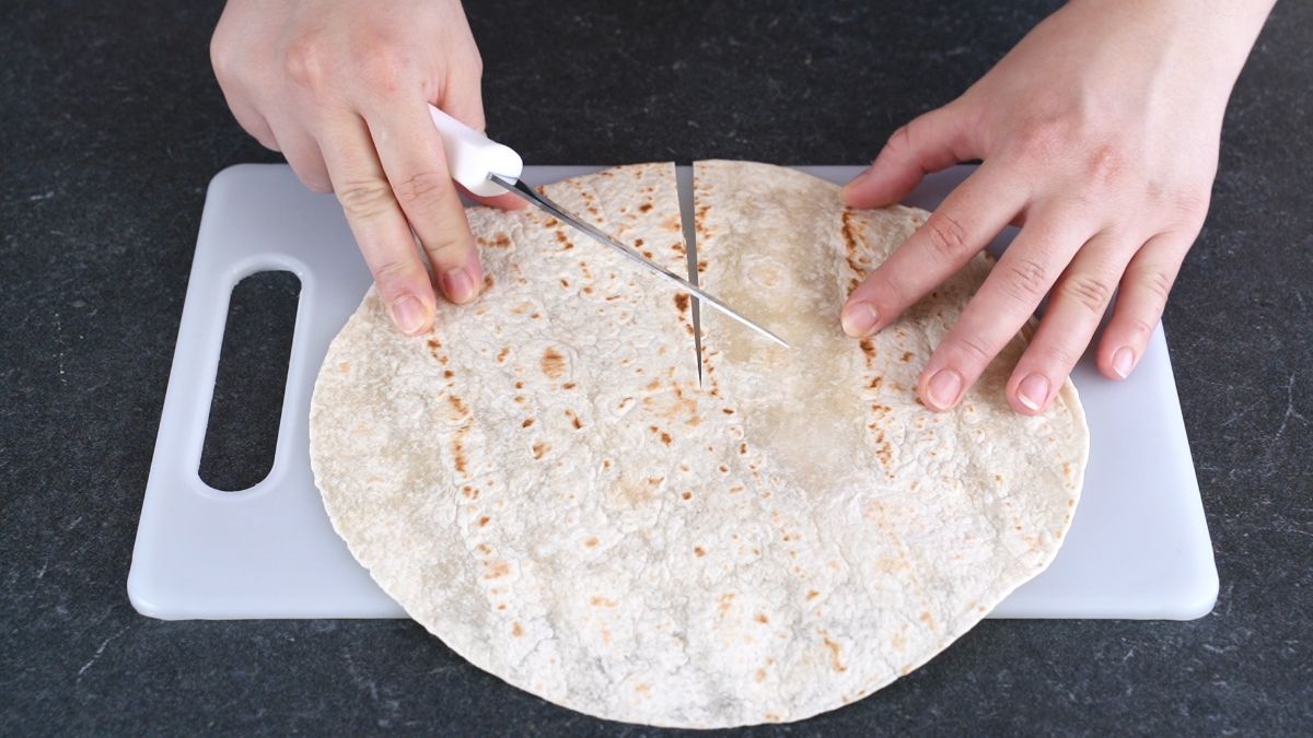 hand holding knife to slice tortilla