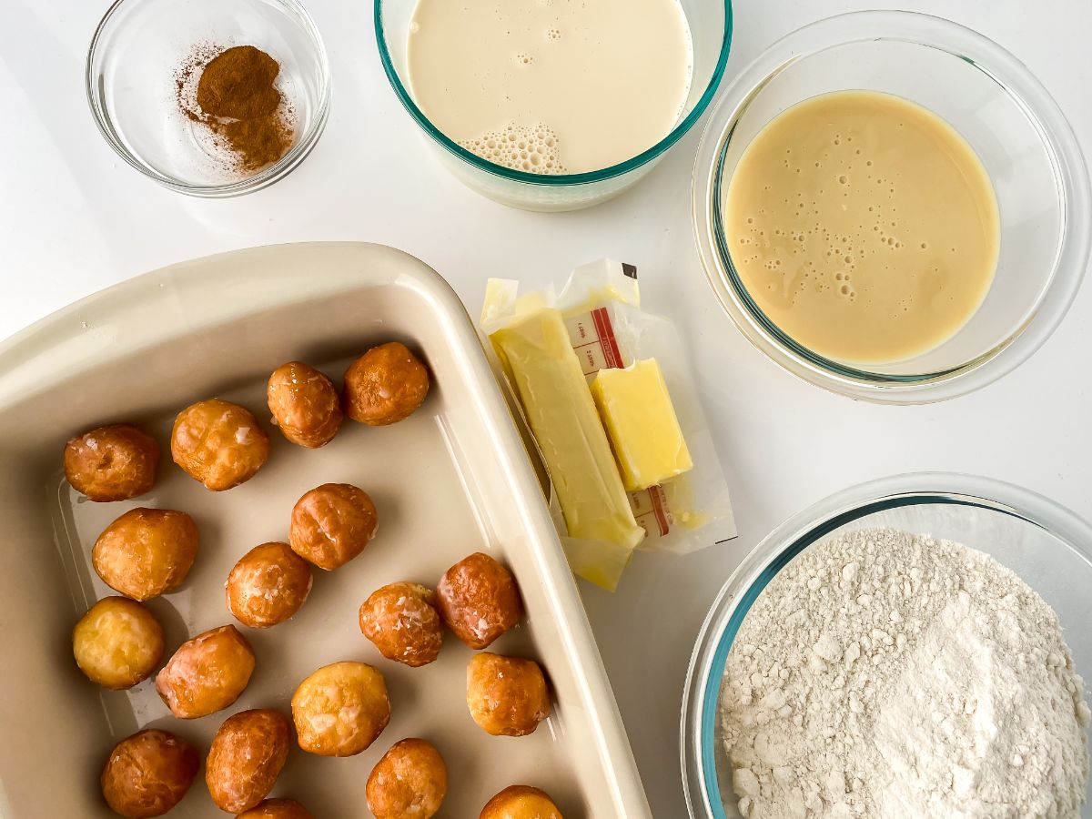 baking dish with donut holes and glass bowls of ingredients on white table