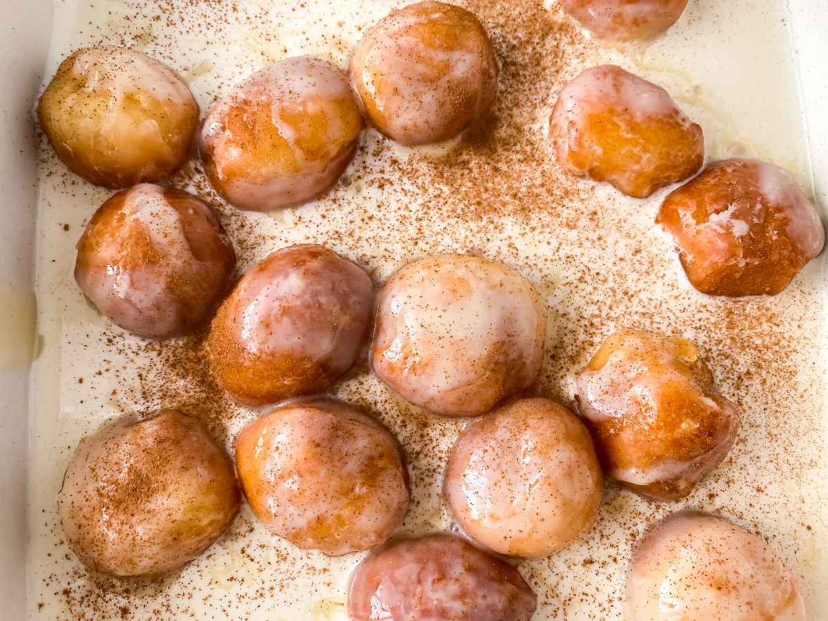 donut holes in pan of cinnamon sugar