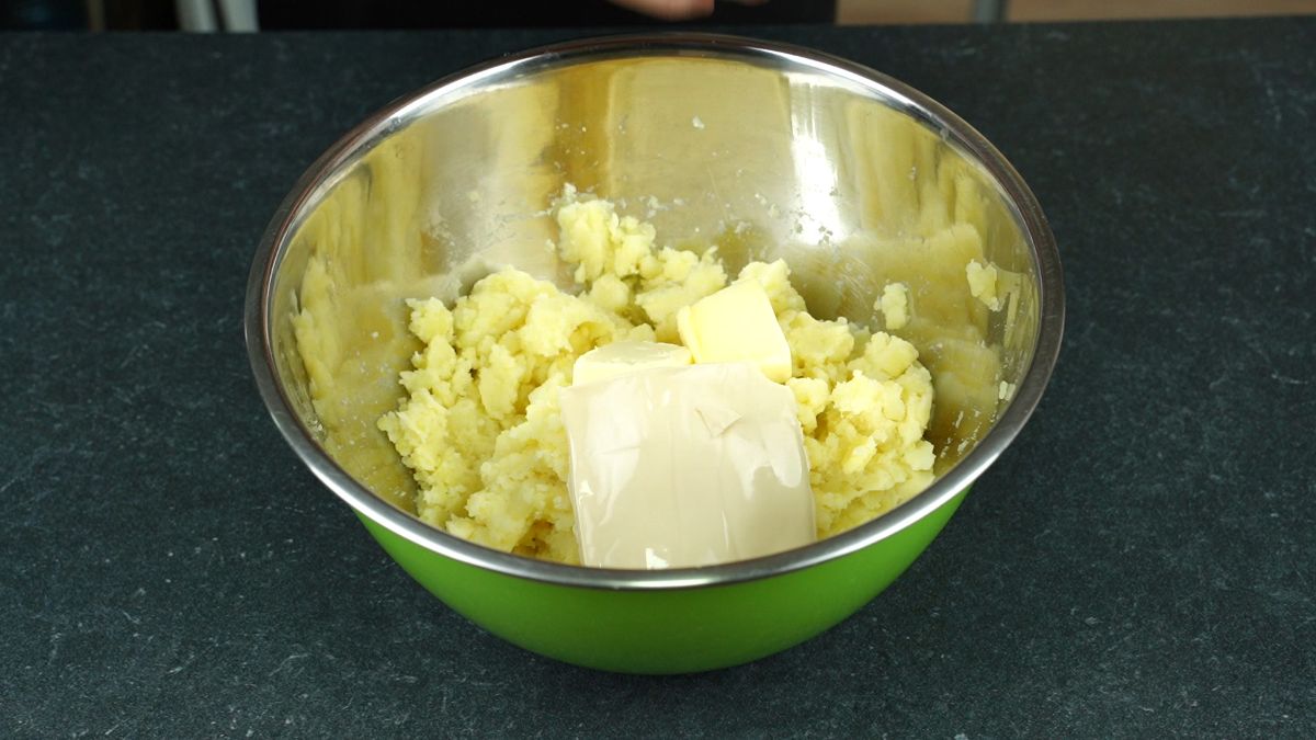 butter on top of potatoes in large green bowl