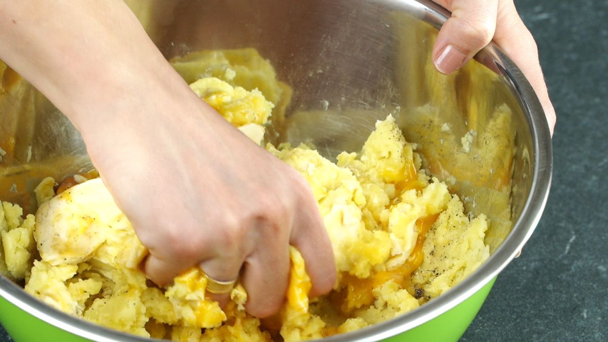 hand mashing potatoes in large bowl