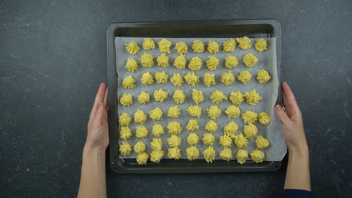 baking sheet of uncooked ptoato bites laying on black table