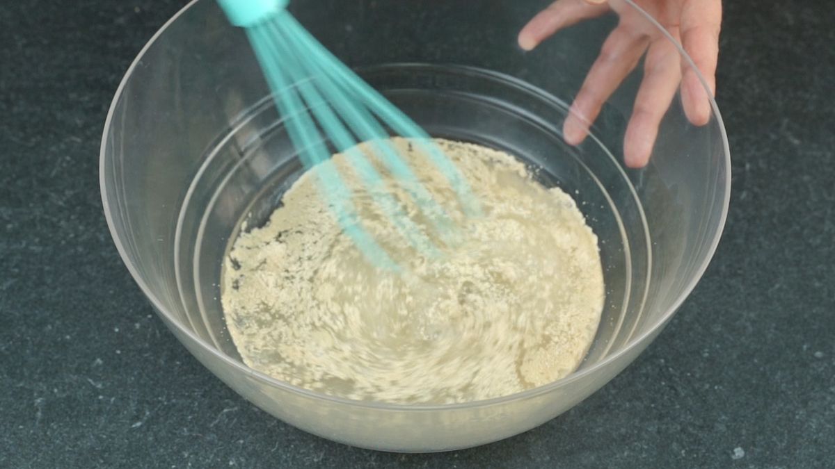 glass bowl of yeast and water with teal whisk