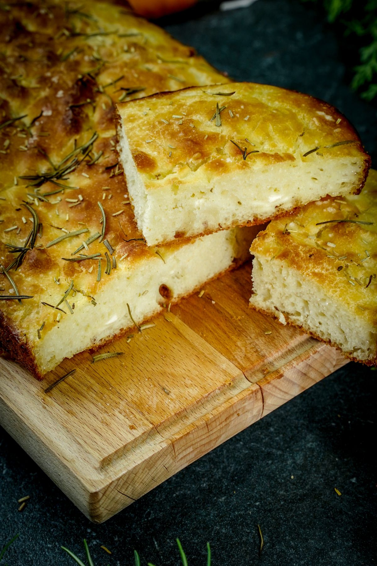 rosemary topped focaccia stacked on cutting board