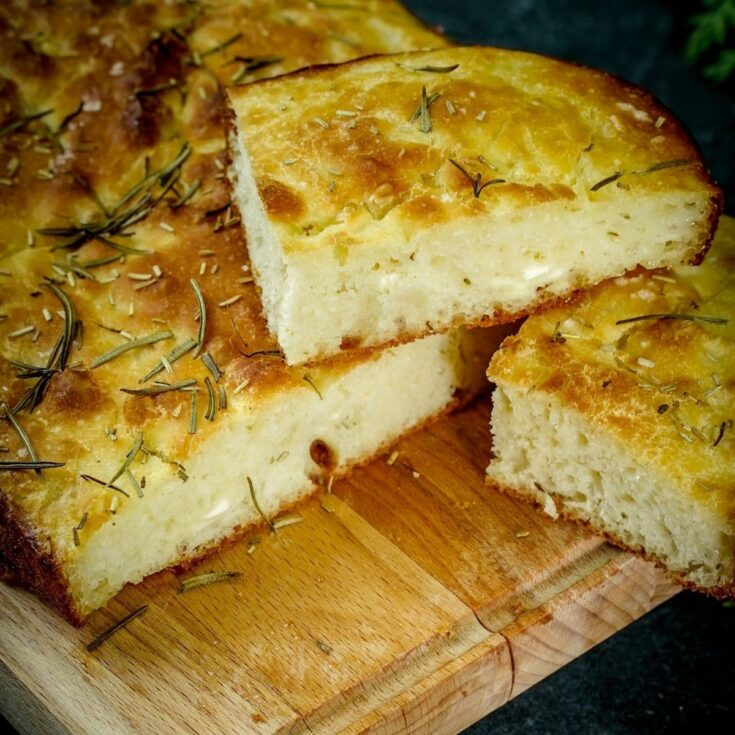 rosemary topped focaccia stacked on cutting board