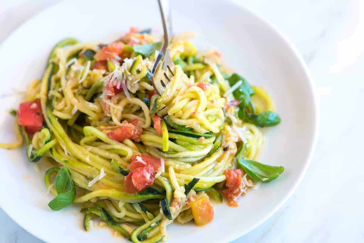 round white bowl of zoodles with tomatoes