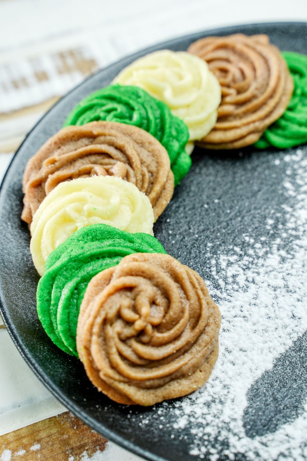 brown green and white butter cookies on black plate