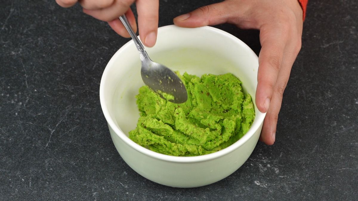 white bowl of green dough with spoon on top