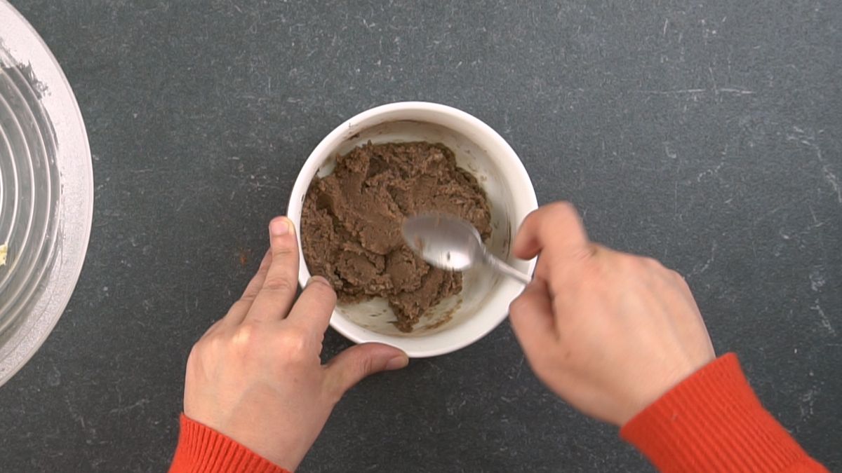 whilte bowl of brown dough with spoon on top