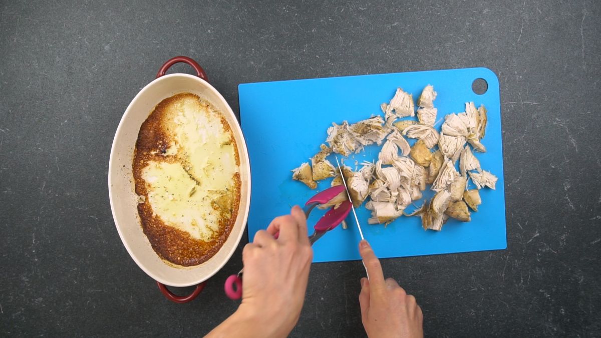 chicken being cut on blue cutting board