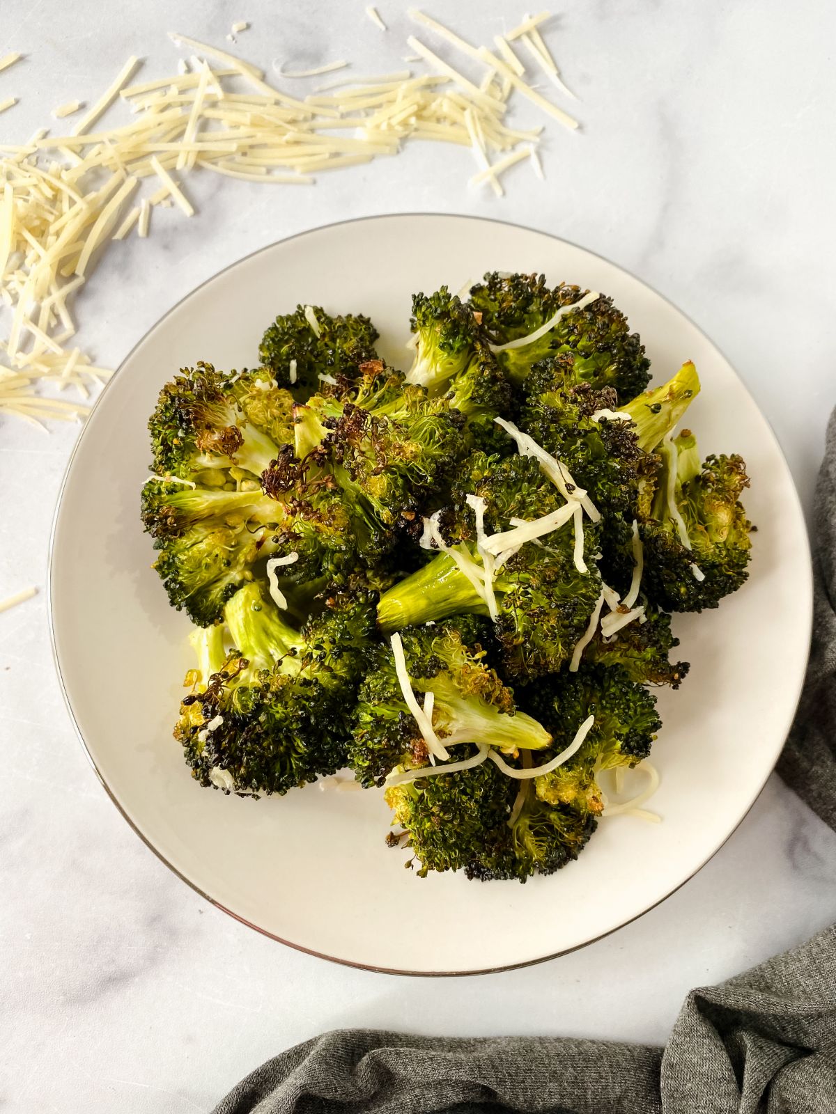 broccoli and cheese on round white plate on marble table