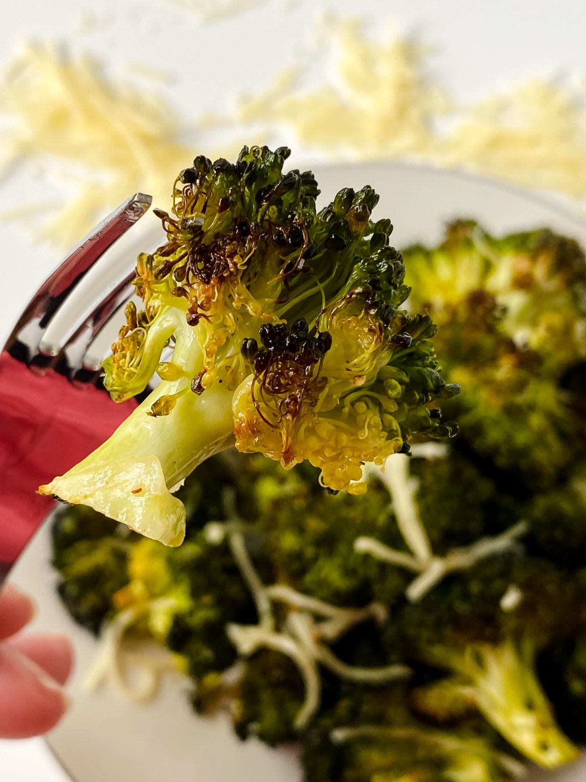 piece of broccoli on fork over bowl of roasted broccoli