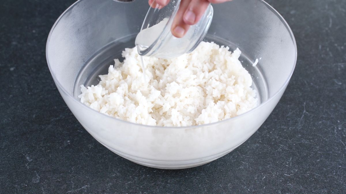 white bowl of rice being mixed with vinegar