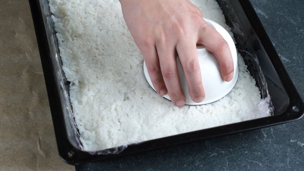 bowl pressing onto rice in baking sheet